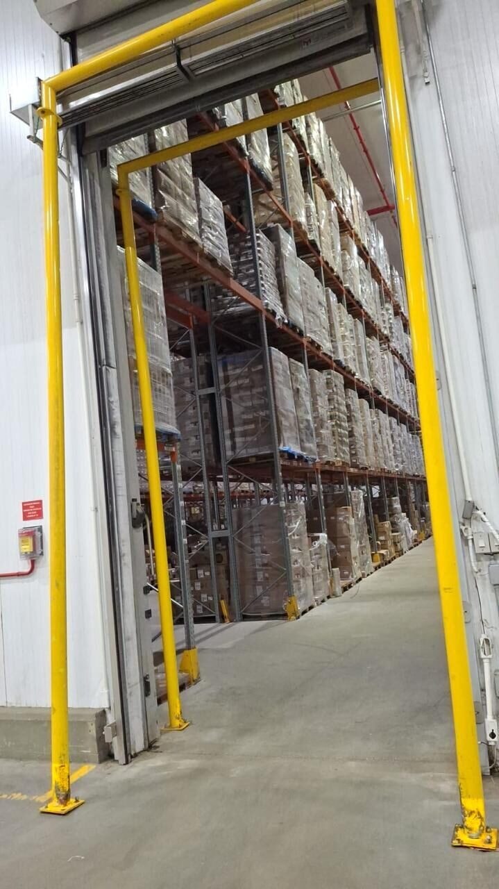 Porta de câmara fria aberta, com o vedante isolante à mostra e o interior refrigerado ao fundo
