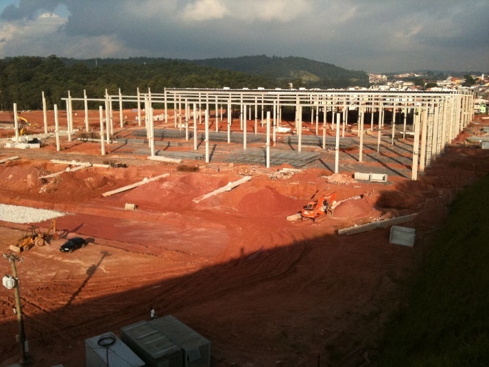 Obra de galpão logístico em andamento, com estrutura metálica de cobertura montada sobre o piso concretado